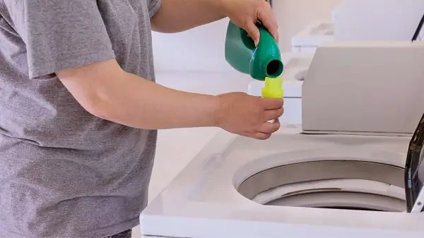 pouring liquid detergent directly into the top load washer