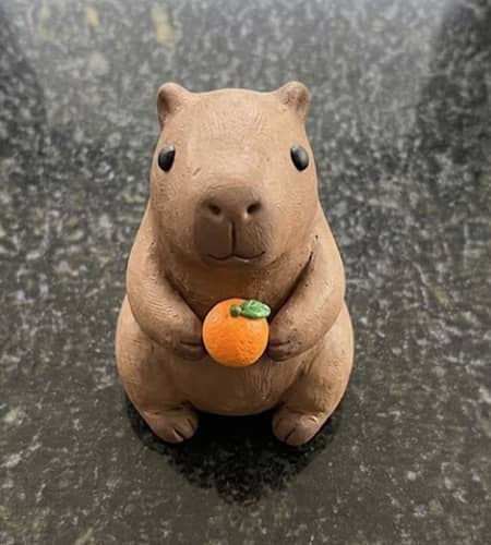 10. Mini Capybara Holding an Orange